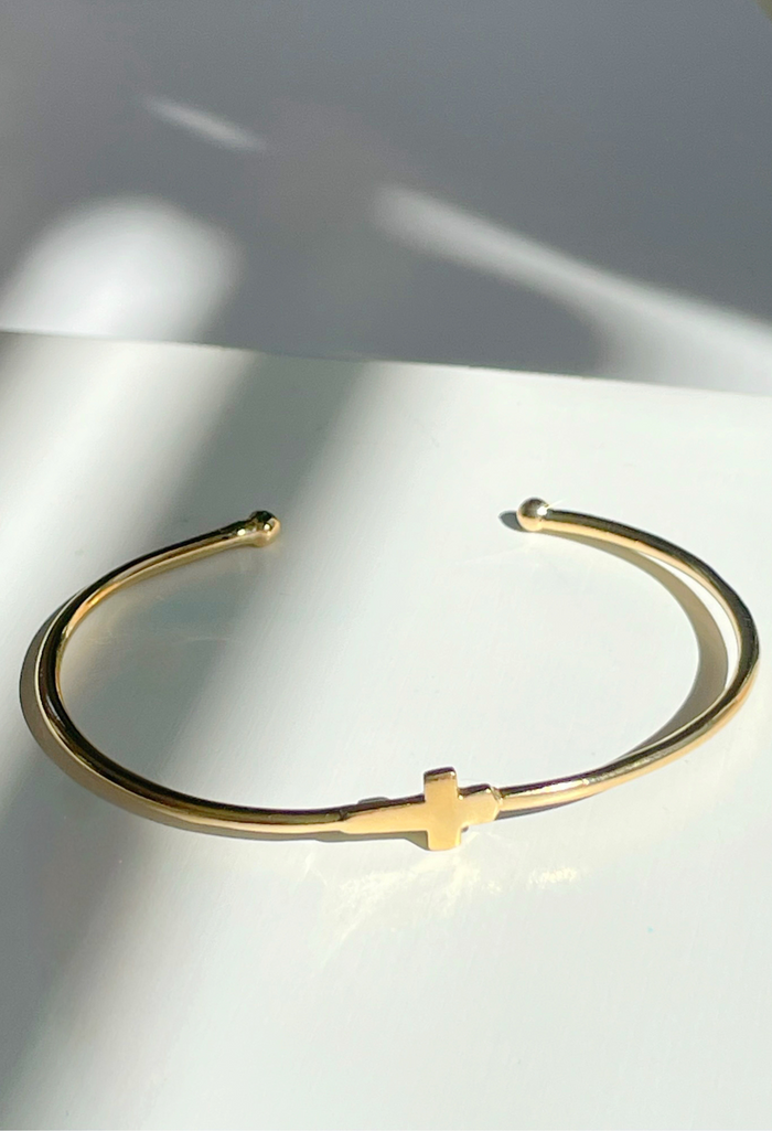 A symbol of faith and love, this dainty 18k gold-filled cross bangle brings timeless meaning to your everyday look—adjustable for the perfect fit.
