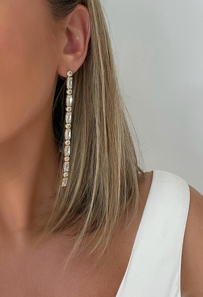 Our CZ Drop Tennis Baguette Earrings shine with Art Deco elegance, featuring sparkling CZ stones in 14k gold-filled settings. A true showstopper for any occasion.