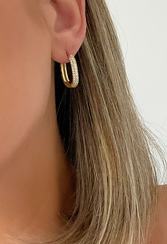 Our Petite Pavé Huggies bring the perfect mix of edge and sparkle. Designed with rows of shimmering crystals on a sleek, oblong-shaped 18k gold-filled hoop, these mini statement-makers add just the right amount of shine to your everyday stack.