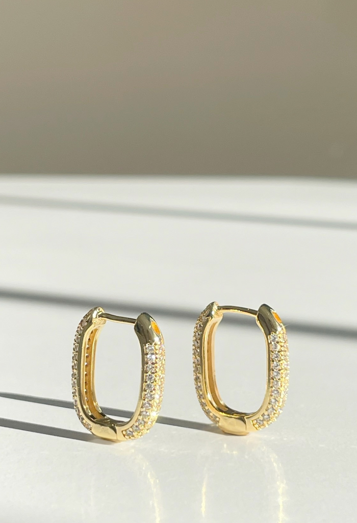 Our Petite Pavé Huggies bring the perfect mix of edge and sparkle. Designed with rows of shimmering crystals on a sleek, oblong-shaped 18k gold-filled hoop, these mini statement-makers add just the right amount of shine to your everyday stack.